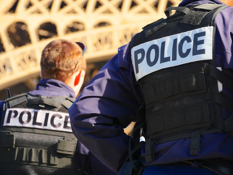 Photographie de deux policiers en uniforme de  dos